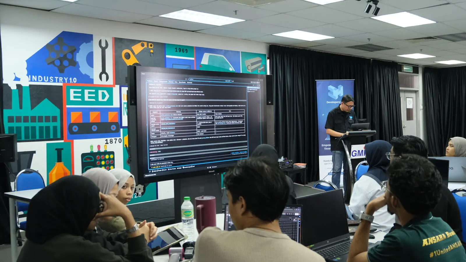 Nasrul Hazim at the podium during the hands-on, with a terminal on the big screen
